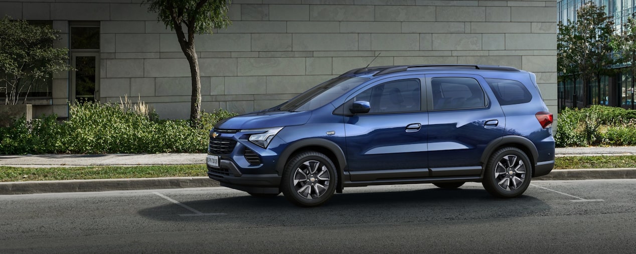 Imagem do novo Chevrolet Spin, na cor Azul Boreal, estacionado em uma avenida.