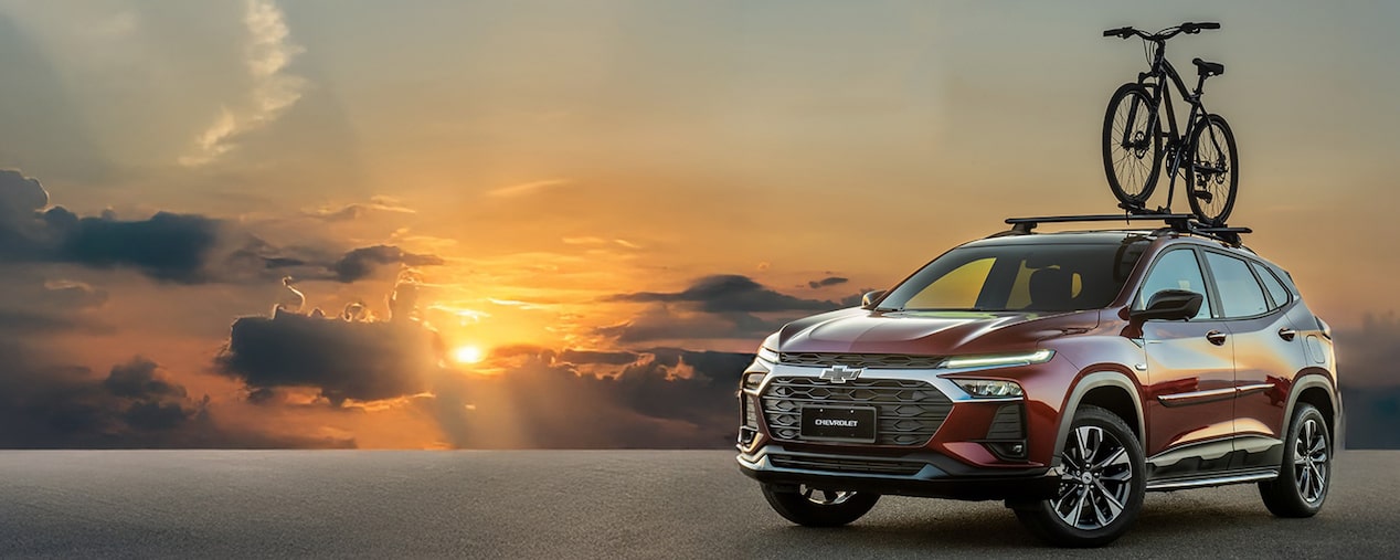 Masthead com Chevrolet Tracker 2026 estacionado em frente ao pôr do sol com uma bicicleta no bagageiro de teto