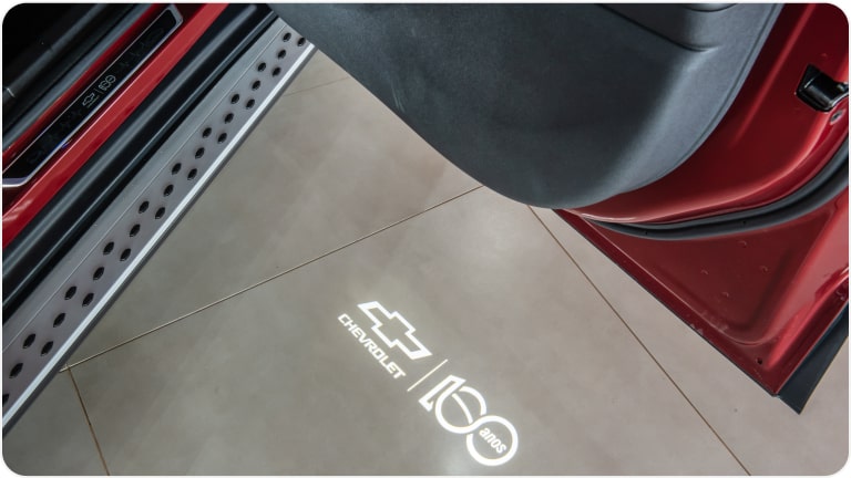 Imagem da luz de cortesia com o logo Chevrolet 100 Anos da linha de acessórios originais Chevrolet para o Tracker 2026