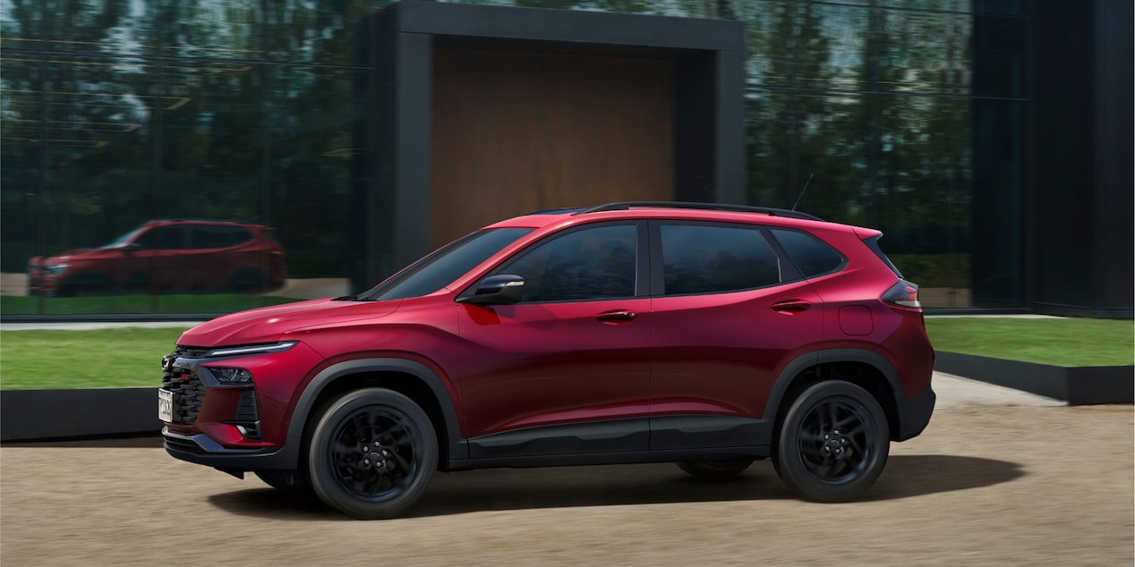 Vista lateral do Chevrolet Tracker RS AT Turbo na cor Vermelho Scarlet, estacionado em ambiente externo.