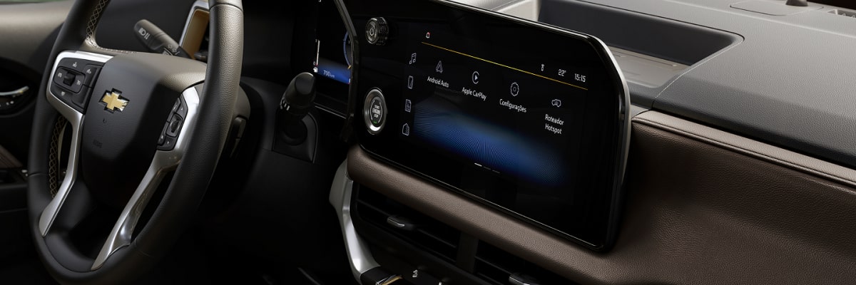 Visão lateral do painel de um Chevrolet Trailblazer; também é possível ver o volante e a central multimídia.