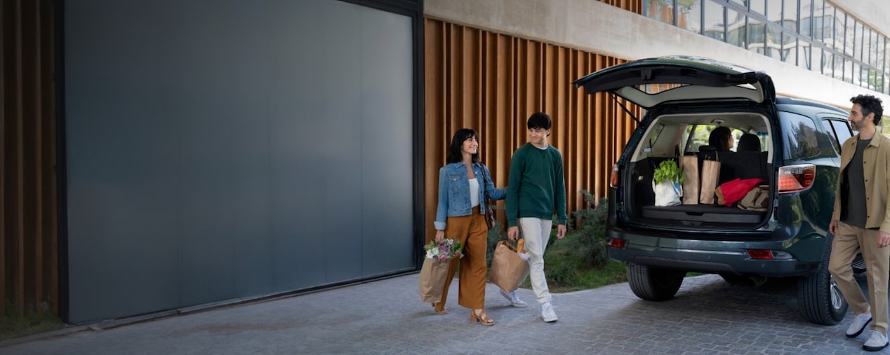 Família em torno de um Trailblazer com o porta-malas aberto com texto sobre acessórios de gerenciamento de carga.