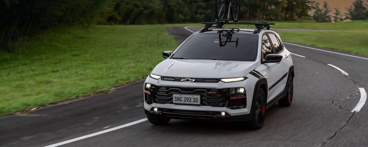 Chevrolet Sonic fazendo uma curva em uma estrada. Em cima do veículo há uma bicicleta fixada no rack de teto. No canto superior esquerdo, o texto "Sonic. Aparência"
