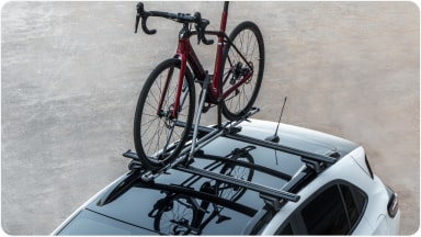 Chevrolet Sonic estacionado em uma área aberta. Em cima do veículo há uma bicicleta fixada no rack de teto.