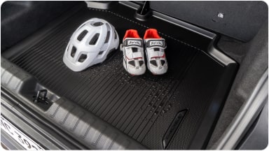 Parte interna do veículo com foco no tapete do porta-malas. Dentro do porta-malas tem um capacete e um par de sapatilhas de ciclismo.