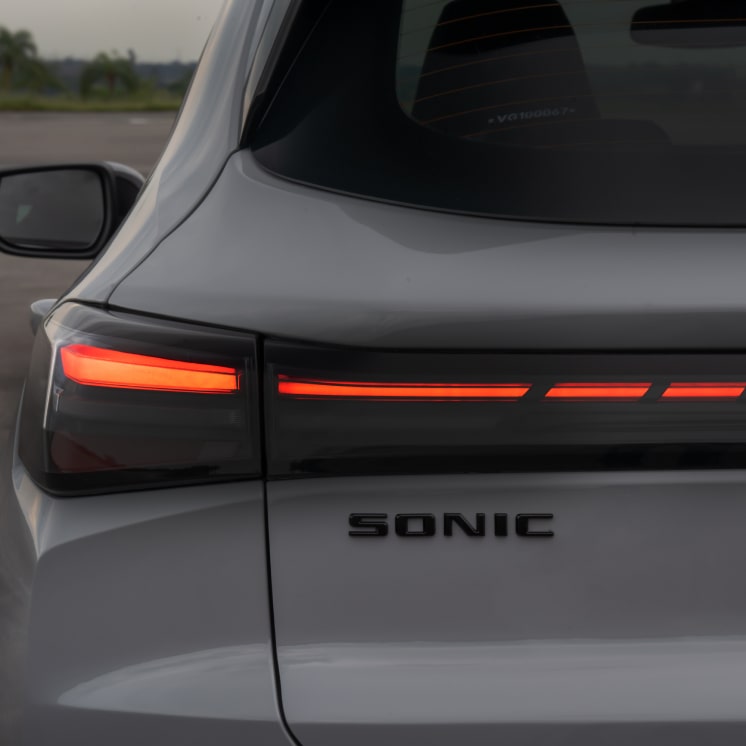 Foco na traseira do Chevrolet Sonic. Destaque as as luzes em LED vermelho e o nome do veículo.
