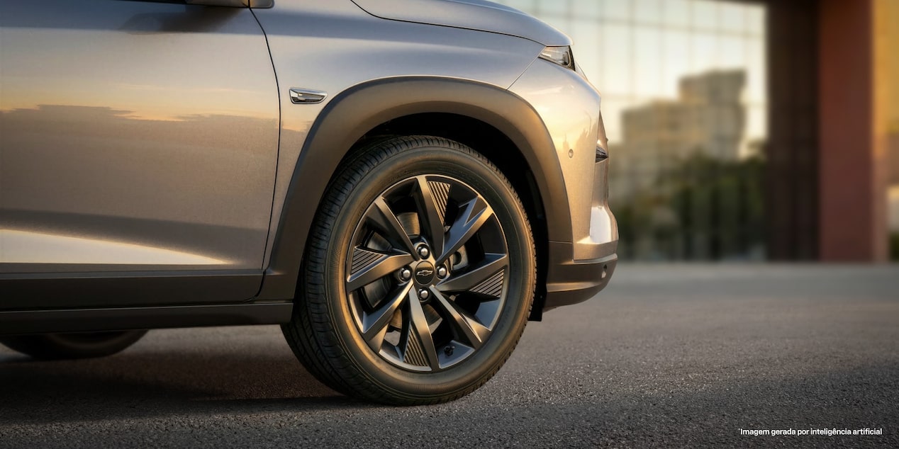 Foco na roda dianteira direita do Chevrolet Sonic. O cenário está em um fim de tarde, dando um tom amarelado para a imagem.​