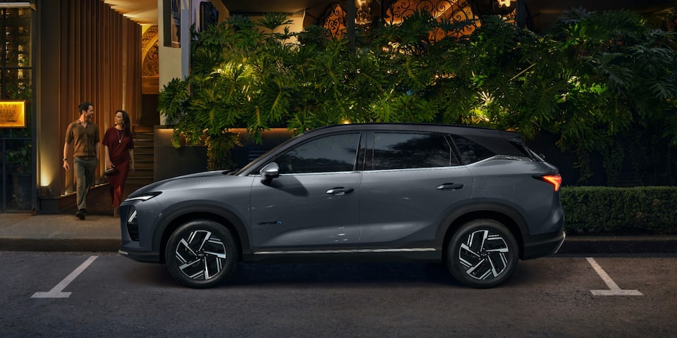 Captiva EV cinza estacionado em frente a um restaurante iluminado, com um casal saindo do local à noite.