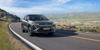 Chevrolet Captiva EV em movimento em uma estrada sinuosa cercada por montanhas e vegetação sob céu azul.