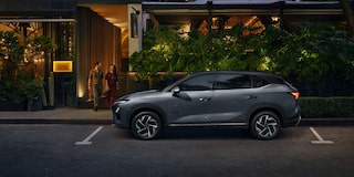 Chevrolet Captiva EV estacionado em frente a um restaurante iluminado, com um casal saindo do local à noite.