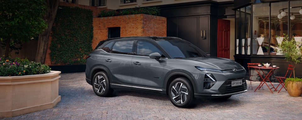 Chevrolet Captiva EV 2026 estacionado em uma rua urbana à noite, com vegetação e fachada iluminada ao fundo.