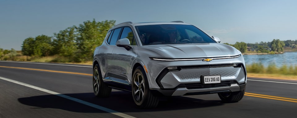Chevrolet Equinox EV 2024 em movimento em uma estrada, com céu azul ao fundo e destaque para opção de assinatura mensal.
