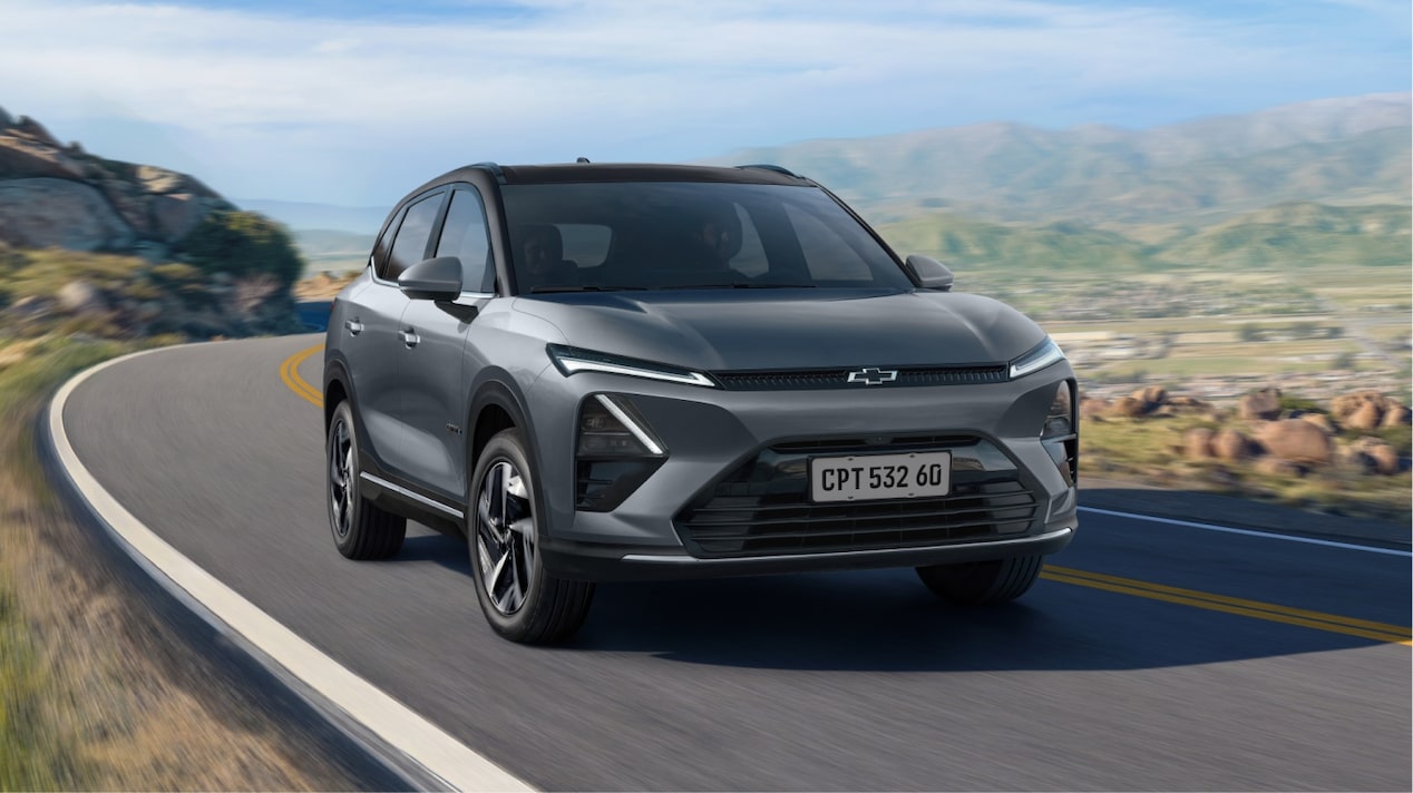 Captiva-Ev chevrolet em movimento em rodovia cercada por montanhas, representando autonomia, tecnologia e condução sustentável.