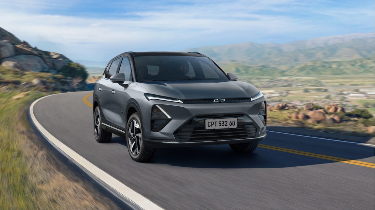 Captiva-Ev chevrolet em movimento em rodovia cercada por montanhas, representando autonomia, tecnologia e condução sustentável.