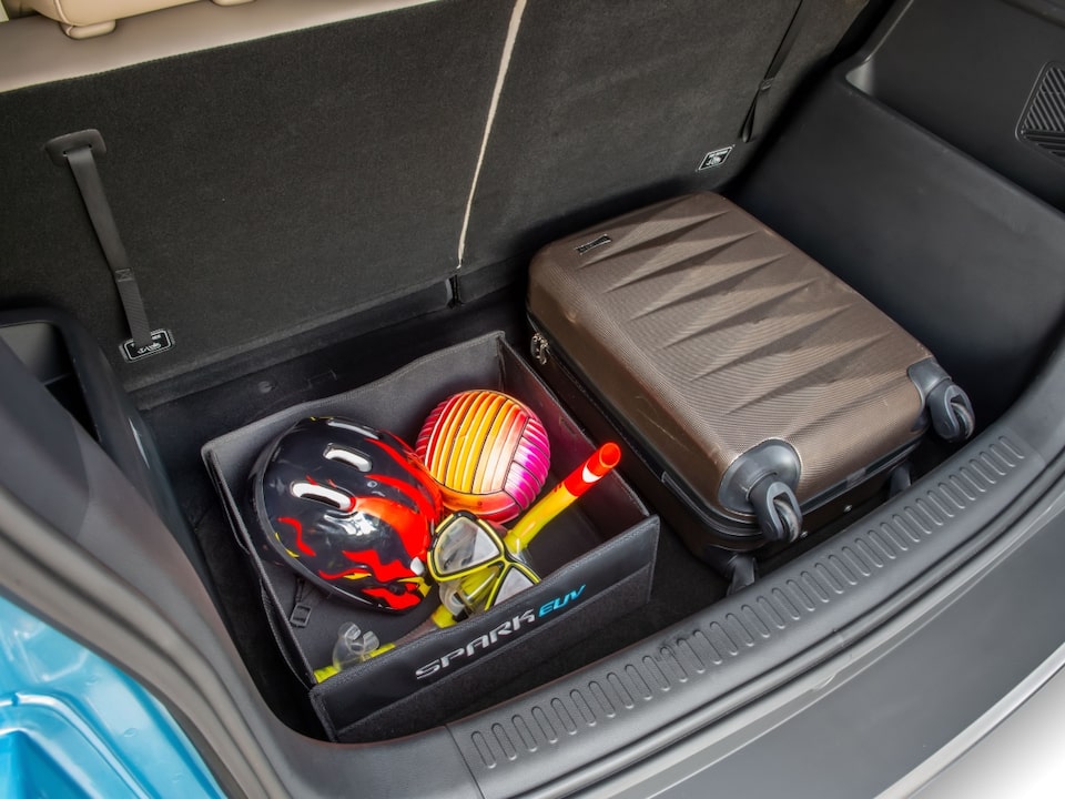 Porta-malas do Chevrolet Spark EUV com mala de bordo e organizador dobrável contendo equipamentos de praia, como máscara de mergulho, snorkel e bola inflável. 
