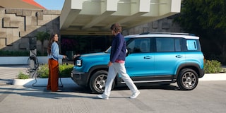 Casal caminha em frente ao Chevrolet Spark EUV Azul Atlântico estacionado.