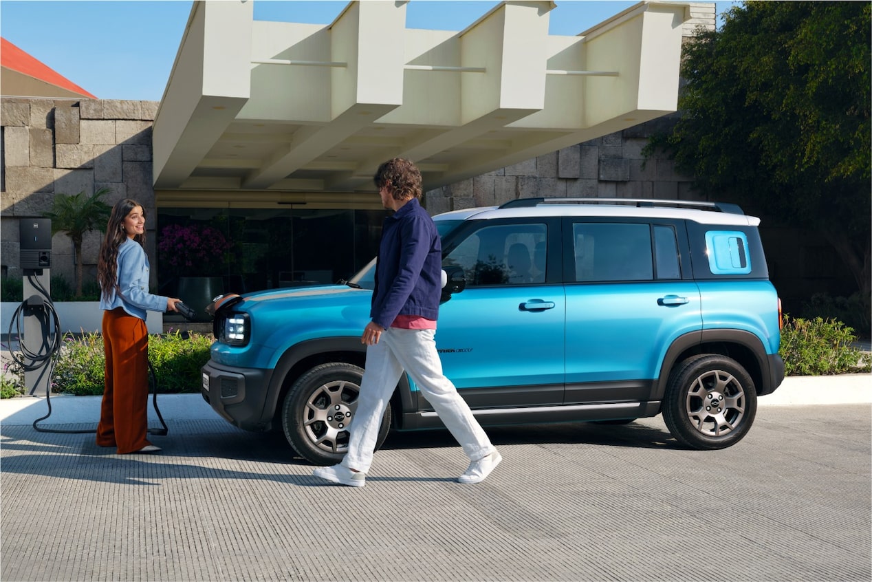Casal caminha em frente ao Chevrolet Spark EUV Azul Atlântico estacionado.