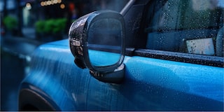 Close do retrovisor do Spark EUV Azul Atlântico com gotas de chuva, destacando o acabamento lateral em um dia chuvoso.