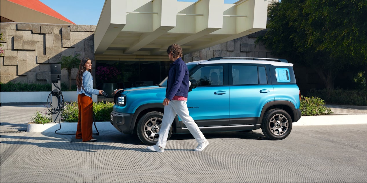 Casal caminha em frente ao Chevrolet Spark EUV Azul Atlântico estacionado.