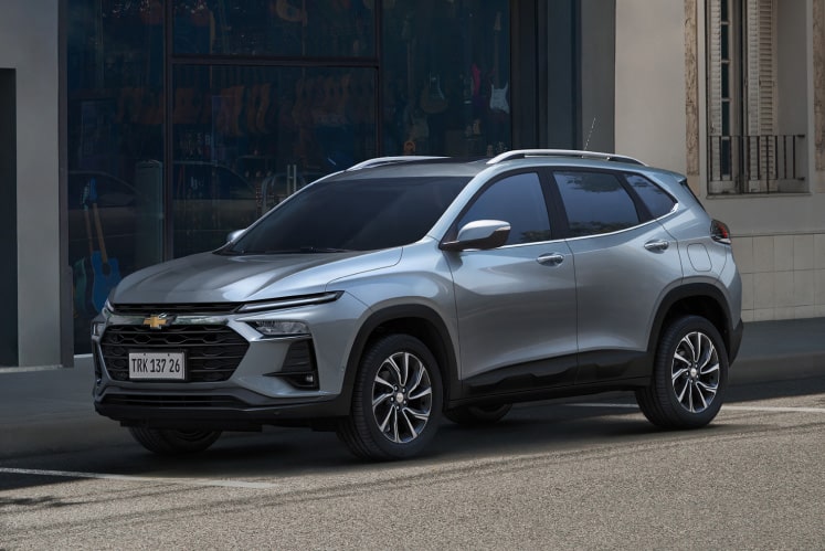 Tracker estacionado em rua de cidade, em frente a prédio moderno.