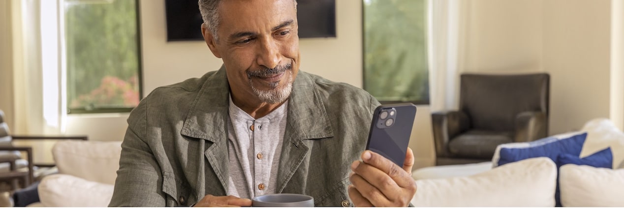 Homem com um celular e uma xícara na mão