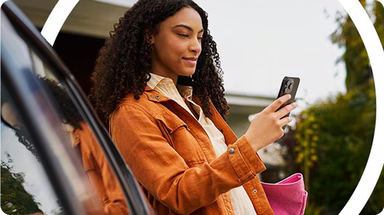 Mulher utilizando o celular ao lado a um Chevrolet.