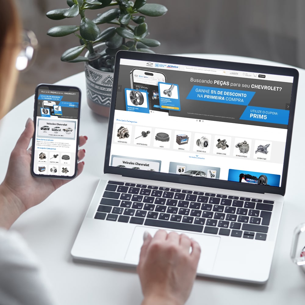 Banner com imagem do ponto de vista de um usuário utilizando o celular e um notebook para acessar o site de Peças Chevrolet