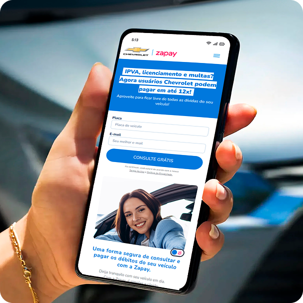 Detalhe de mão feminina segurando um celular cuja tela exibe a solução de pagamento Zapay.