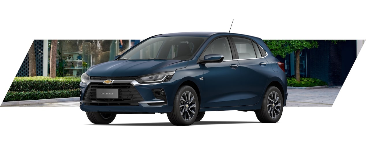 Chevrolet Onix hatch em vista de frente e lateral, posicionado em área urbana com árvores e fachadas ao fundo.