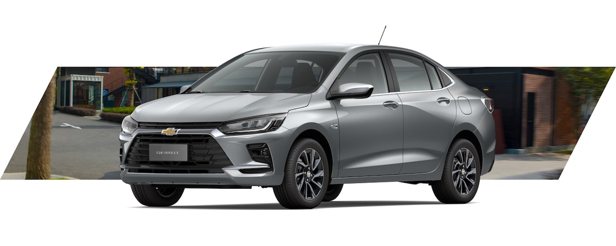 Onix Plus em vista de frente e lateral, com fundo urbano desfocado e iluminação suave.