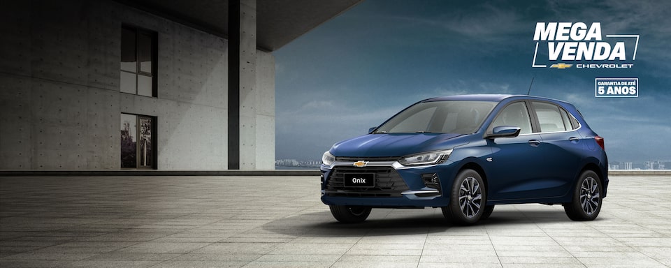 Banner promocional do Chevrolet Onix azul estacionado em piso de concreto, com o texto Novo Onix – oportunidades imperdíveis a partir de R$ 84.990 ou entrada de R$ 52.450 e 48 parcelas de R$ 990. À direita, selo Mega Venda Chevrolet – garantia de até 5 anos.