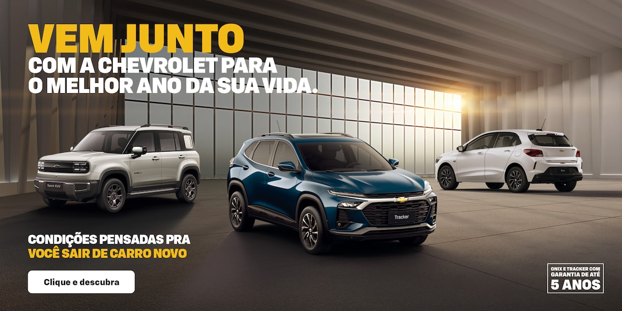 Banner predominantemente escuro, com um Spark EUV, Tracker e um Onix, dispostos em ordenação triangular diante de uma grande janela por onde entra a luz que alumia a cena. No quadrante superior esquerdo, o texto: Vem junto com a Chevrolet para o melhor ano da sua vida. No quadrante inferior esquerdo, com um texto condições pensadas pra você sair de carro novo. No quadrante inferior direito, o selo de 5 anos de garantia Chevrolet.
