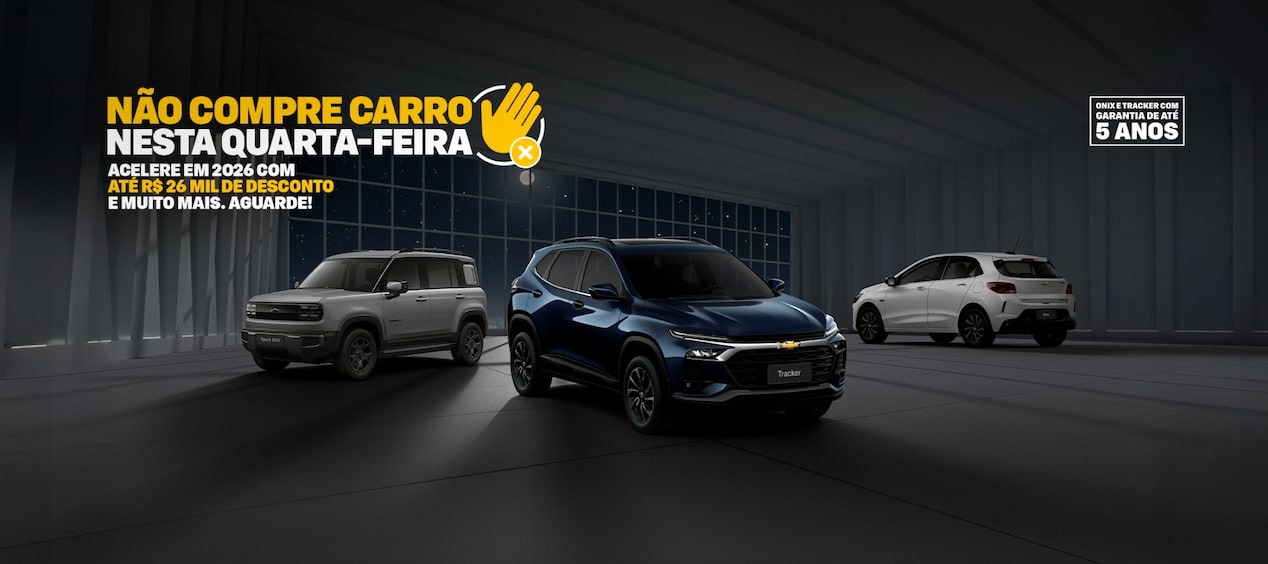 Banner predominantemente escuro ilustrado por um Tracker, Onix e Spark EUV  – dispostos com composição triangular dentro do quadro. No quadrante superior esquerdo, o texto: Não compre carro nessa quarta-feira, acompanhado de um ícone que representa o veto (uma mão e um X); abaixo, o complemento: acelere em 2026 com descontos de até 26 mil e muito mais, aguarde. No pé da imagem há o selo de 5 anos de garantia.
