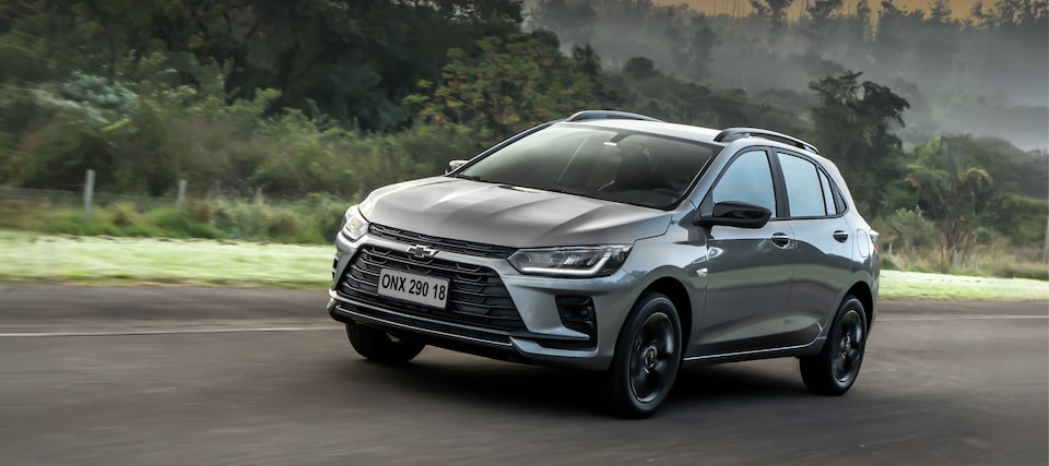 Chevrolet Onix Activ prata em imagem ambientada na cidade; no quadrante superior esquerdo, o texto: Novo Onix Activ - mais alto, mais versátil, mais Activ, logo abaixo, o botão: Saber mais.