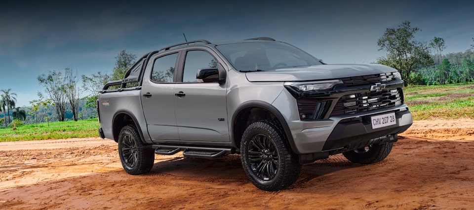 Chevrolet S10 Trail Boss Prata estacionada em um ambiente externo em uma estrada de terra. Ao fundo, temos arbustos e algumas árvores.