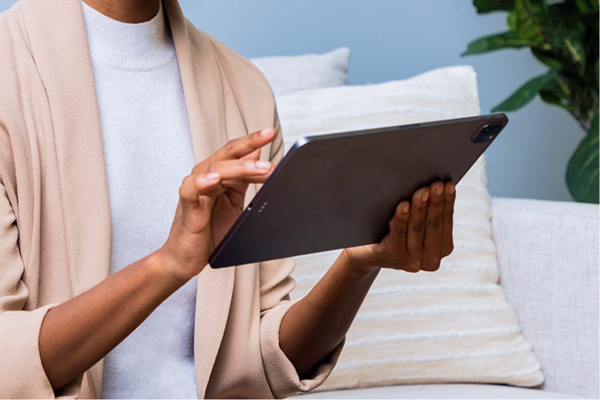 uma mulher consultando os manuais do seu veículo em um tablet na sala de casa.