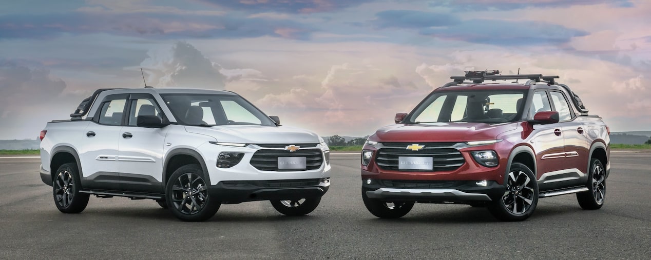 Chevrolet Montana branca e Chevrolet Montana vermelha em foto ambientada, estacionadas uma de frente para a outra a céu aberto. No quadrante superior esquerdo, o texto: Montana - acessórios.