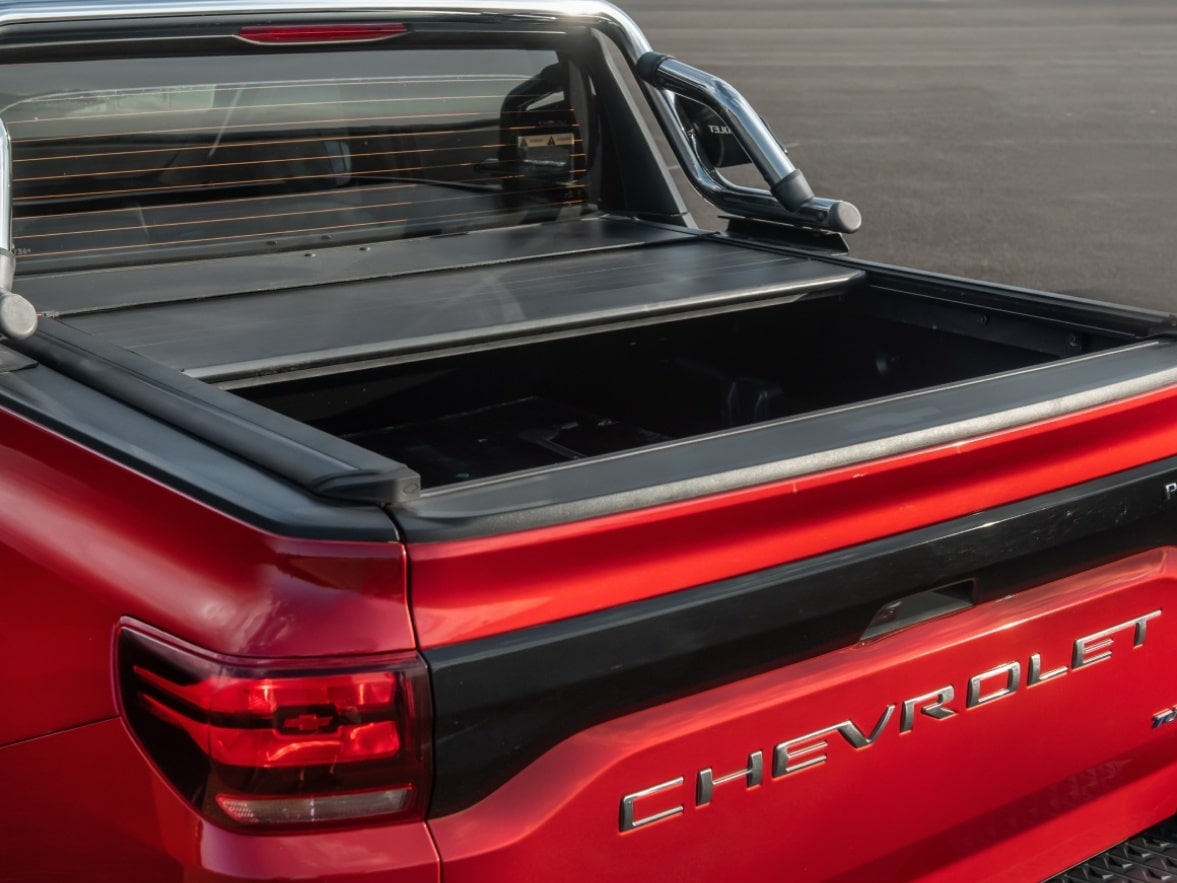 Visão traseira da Chevrolet Montana com foco na caçamba e na capota elétrica rígida de lona marítima.