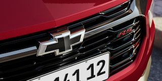 Close da grade frontal da Chevrolet Montana na cor Vermelho Scarlet com logotipo Chevrolet preto e emblema RS