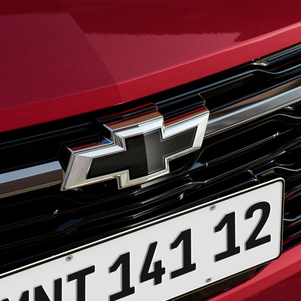 Close da grade frontal da Chevrolet Montana na cor Vermelho Scarlet com logotipo Chevrolet preto e emblema RS