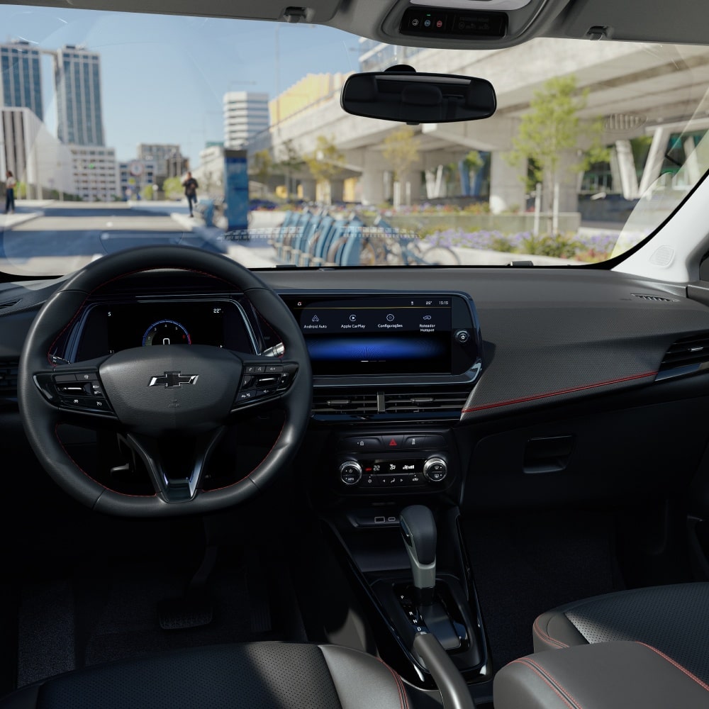 Volante e painel da Chevrolet Montana com acabamento escurecido e fundo de cidade urbana ao dia