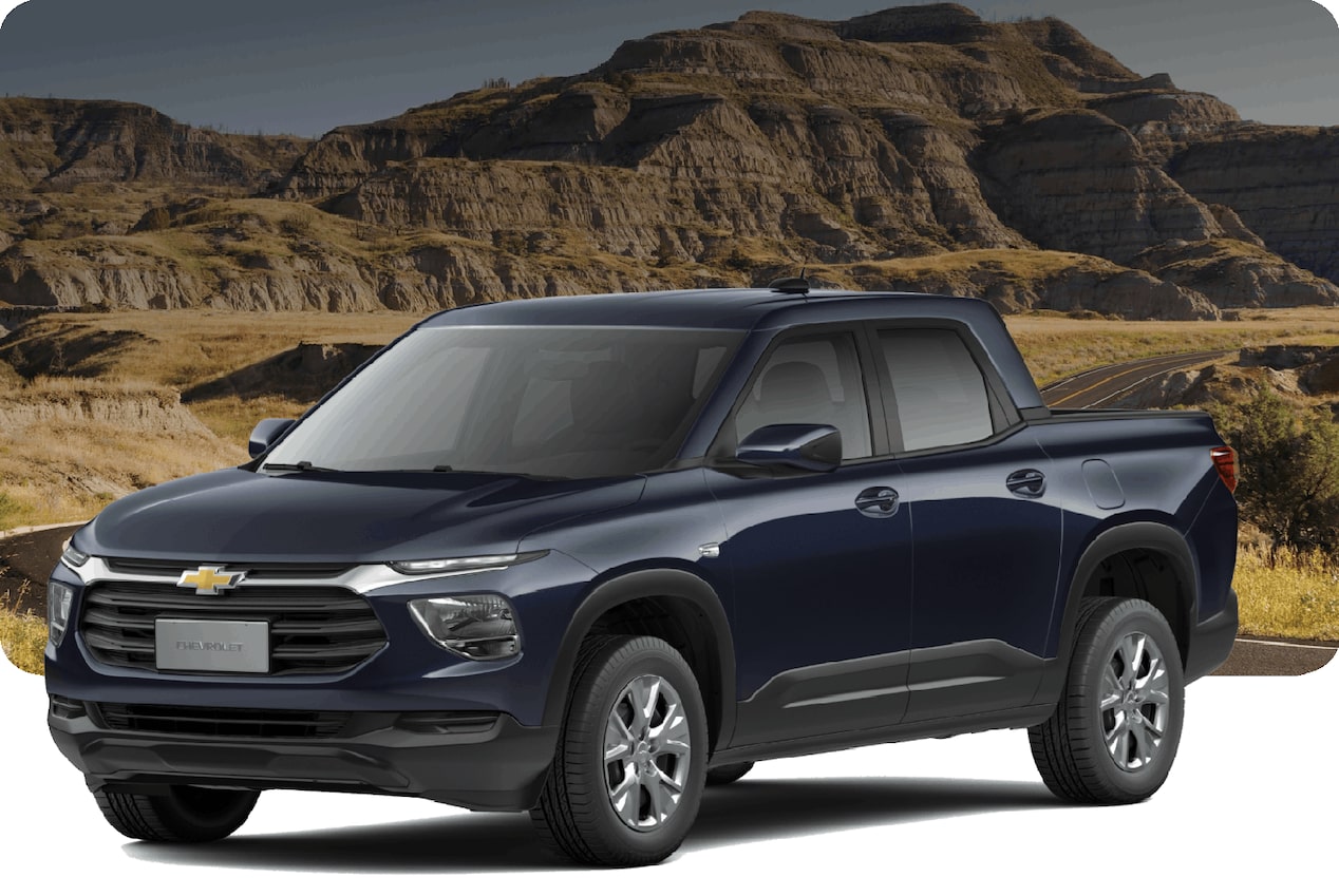 Chevrolet Montana cinza em estrada de terra com montanhas rochosas ao fundo