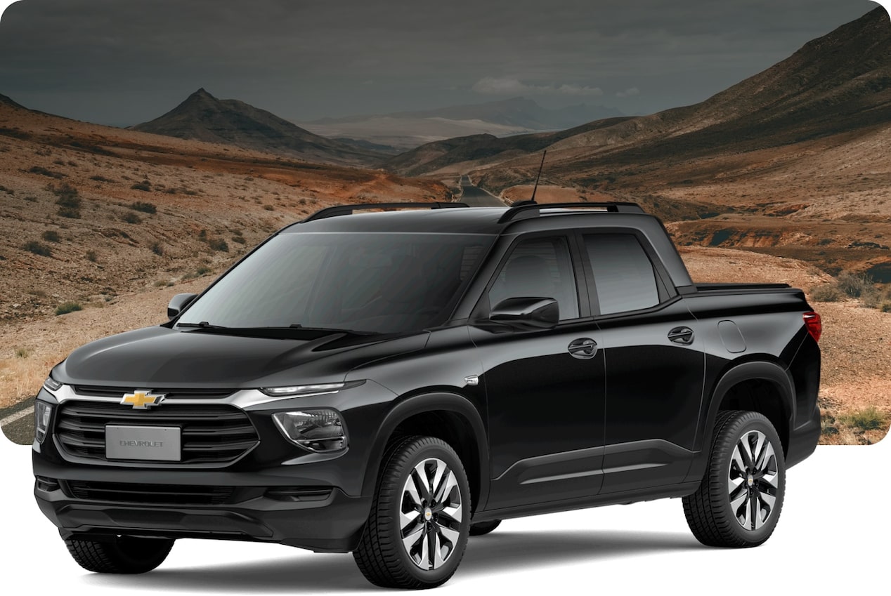 Chevrolet Montana preta em paisagem desértica com céu amarelado e montanhas ao fundo