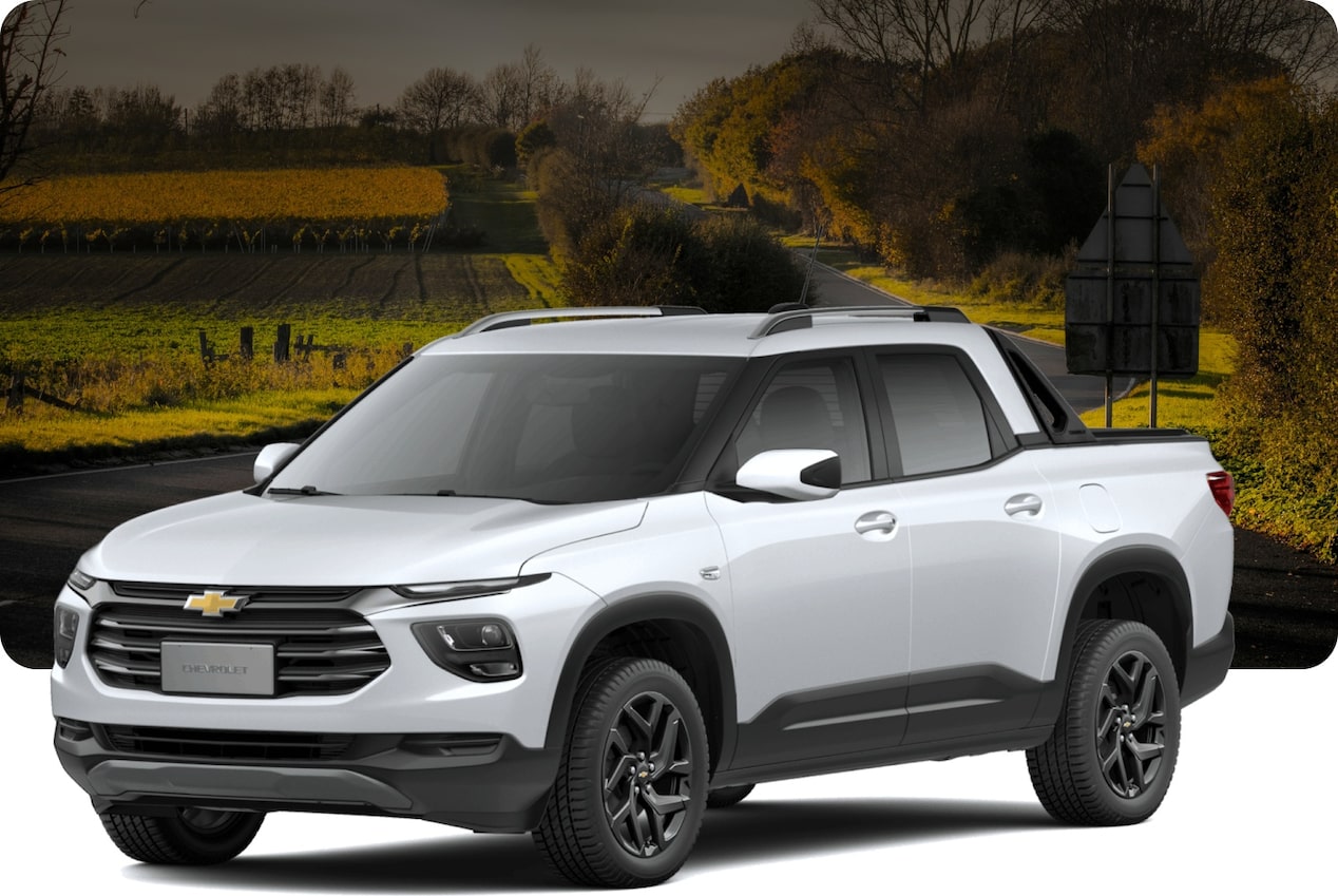 Chevrolet Montana branca em paisagem dourada de campo aberto com árvores ao fundo