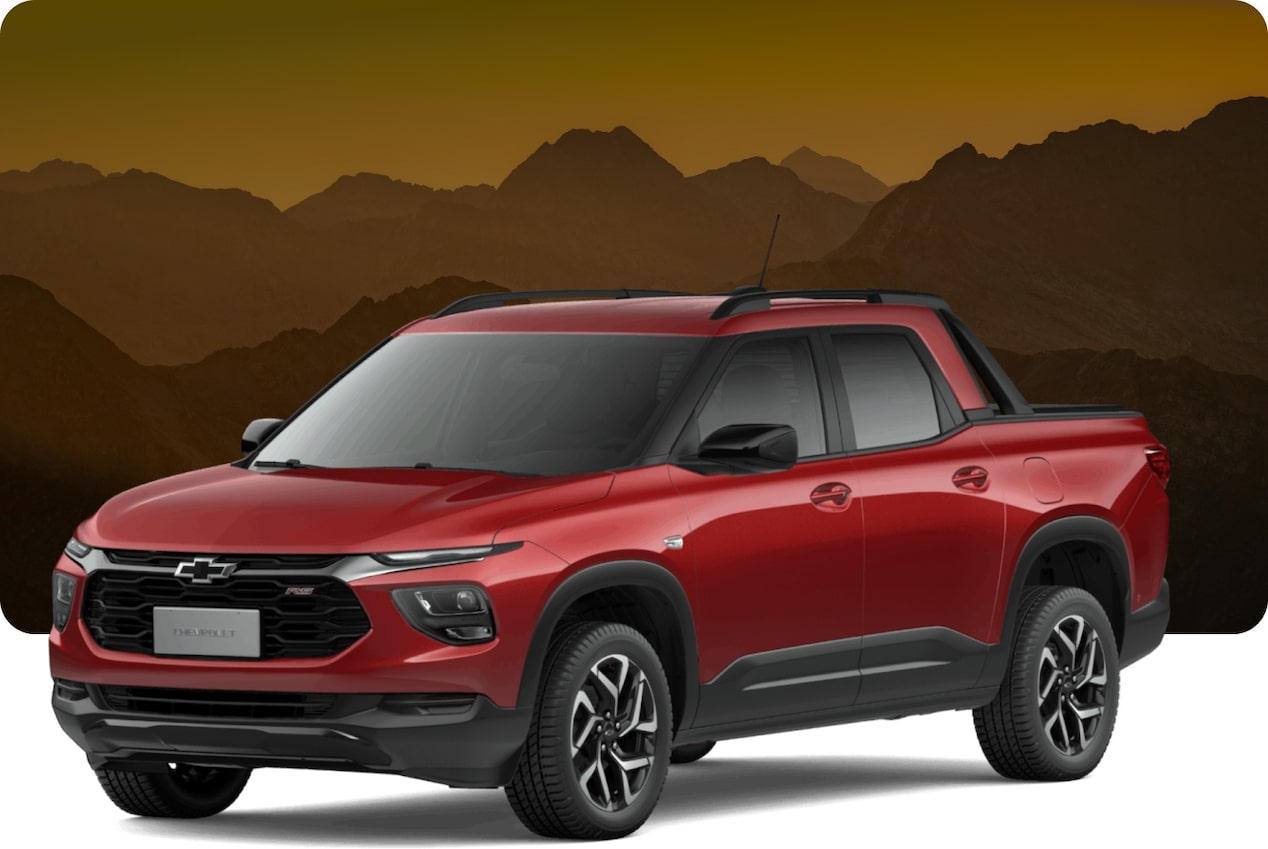 Chevrolet Montana vermelha em destaque contra cenário montanhoso e céu alaranjado ao entardecer