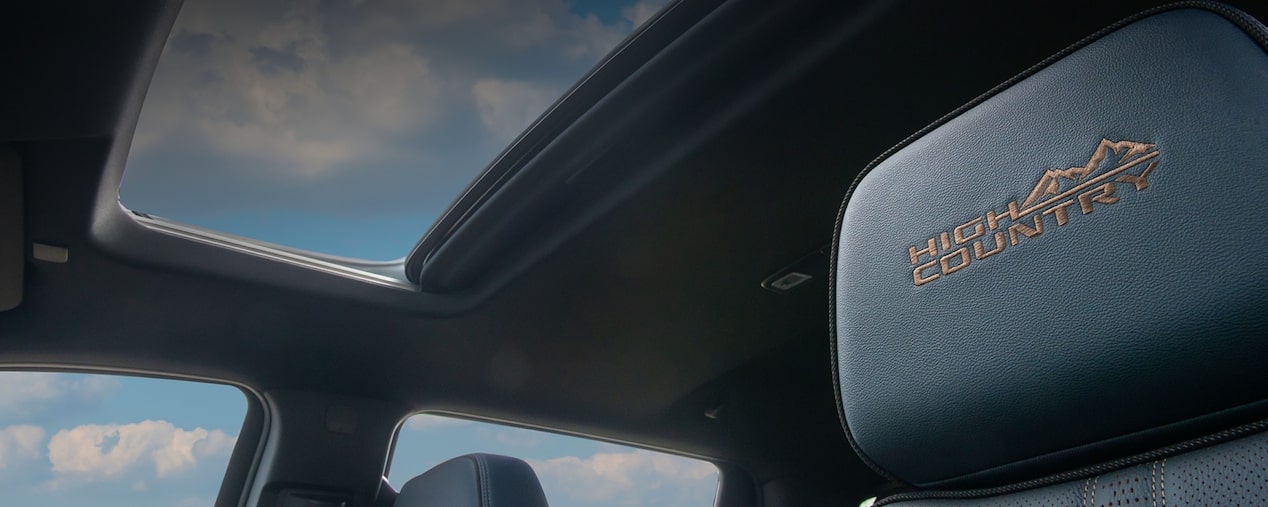 Mastehead da página de Conforto dos acessórios originais Chevrolet para a picape Silverado, onde vemos o teto solar panorâmico encimado por céu azul e poucas nuvens. 