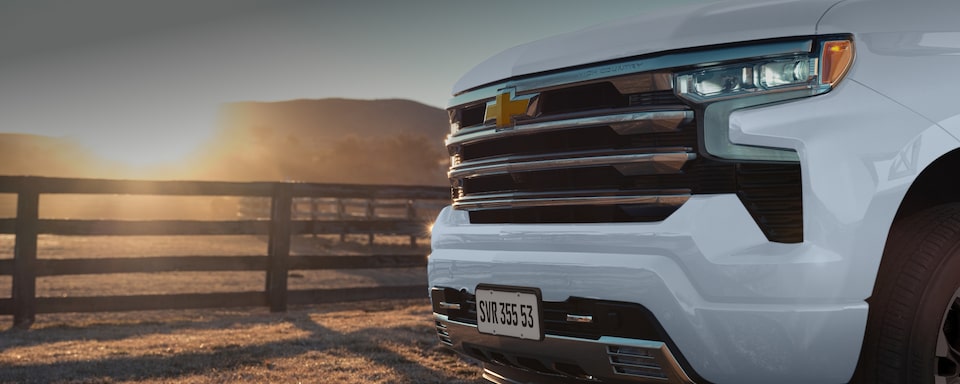Mastehead da página de Pacotes dos acessórios originais Chevrolet para a picape Silverado, que aparece em imagem ambientada no campo.