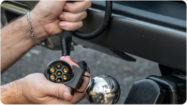 Imagem mostrando as mão de um homem instalando o acessório adaptador de engate, na traseira da nova picape Chevrolet Silverado.