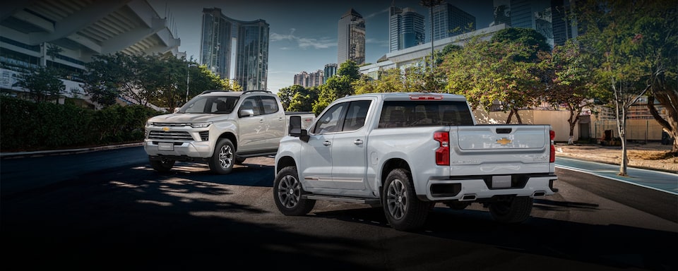 Portfólio de picapes Chevrolet ilustrado por S10 e Silverado dispostas em imagem ambientada com prédios espelhados compondo o segundo plano.