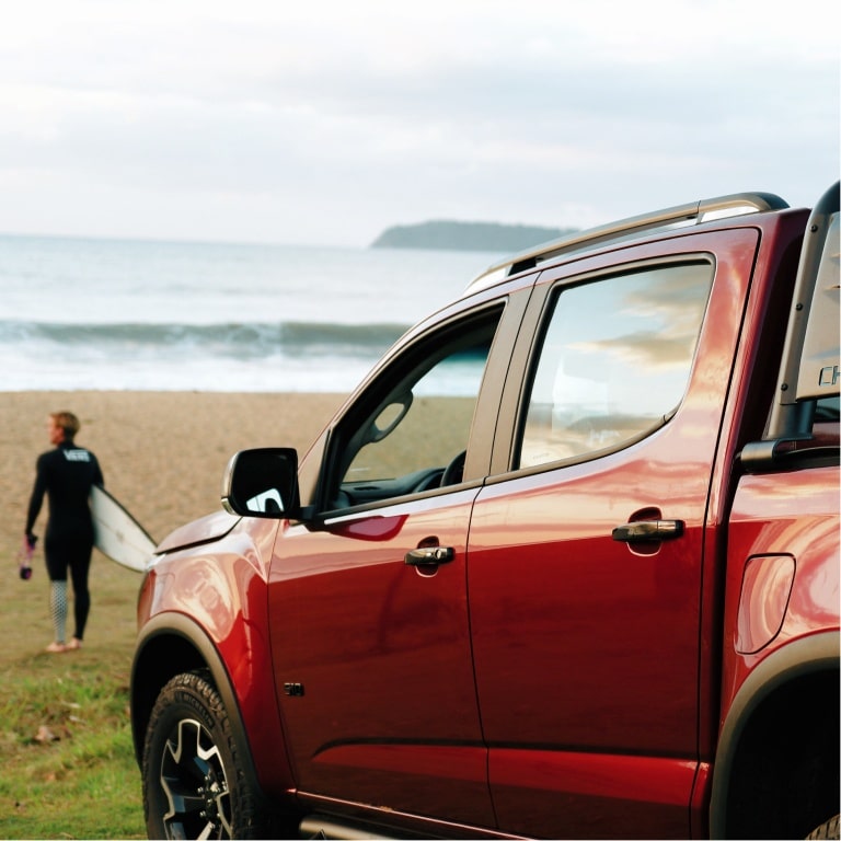 Surfista estaciona Chevrolet S10 para depois entrar no mar e pegar altas ondas.